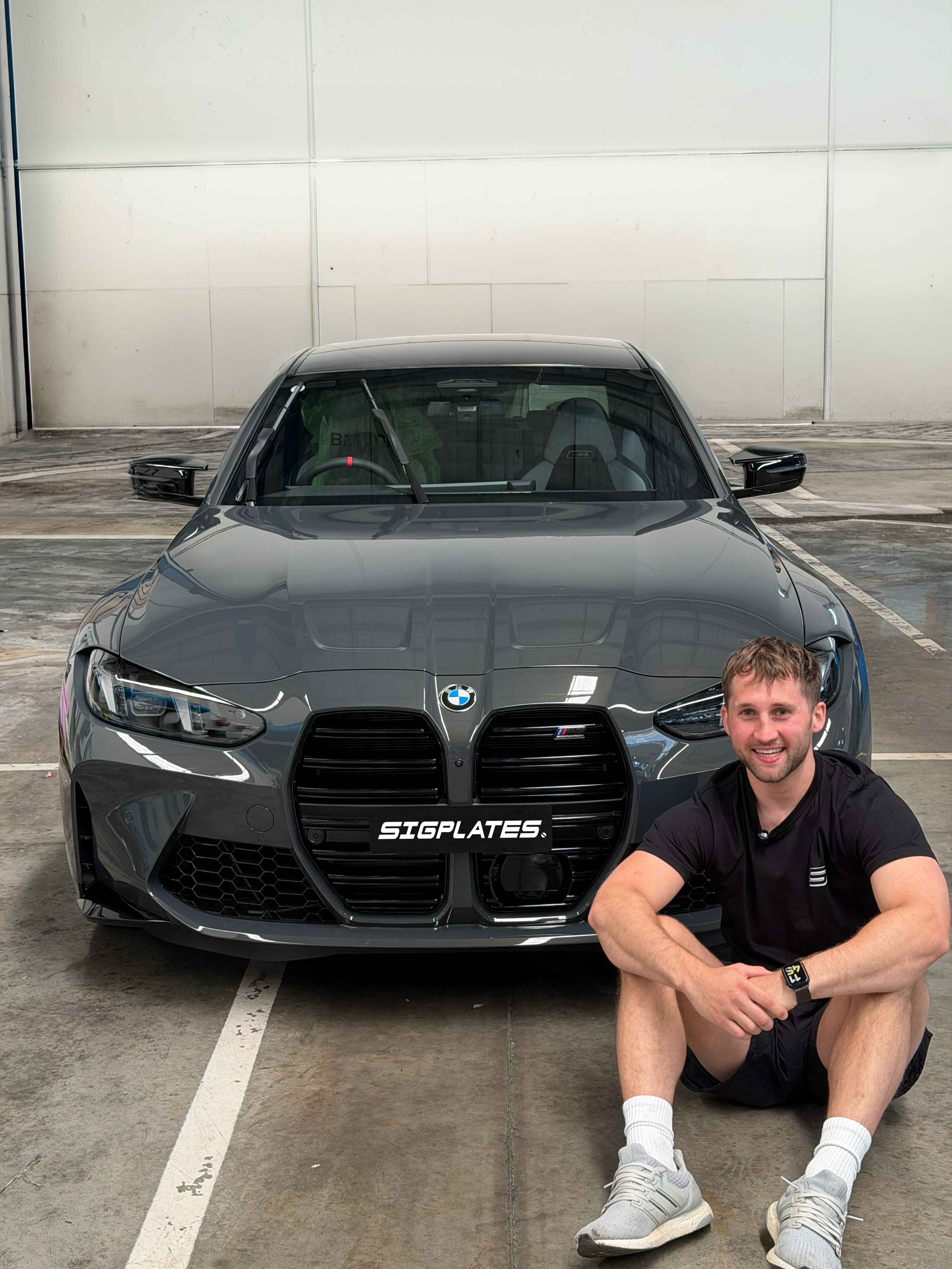 Ethan from Sigplates next to a BMW M3 with freshly installed plates